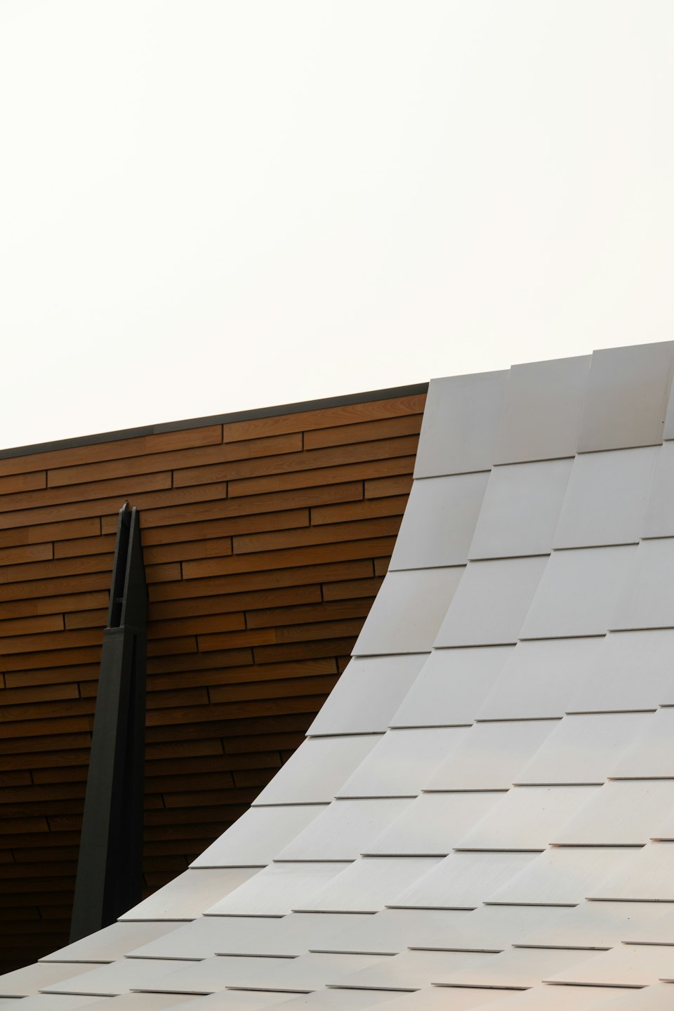 Modern rectangular building panels meet a dark wooden slatted wall.