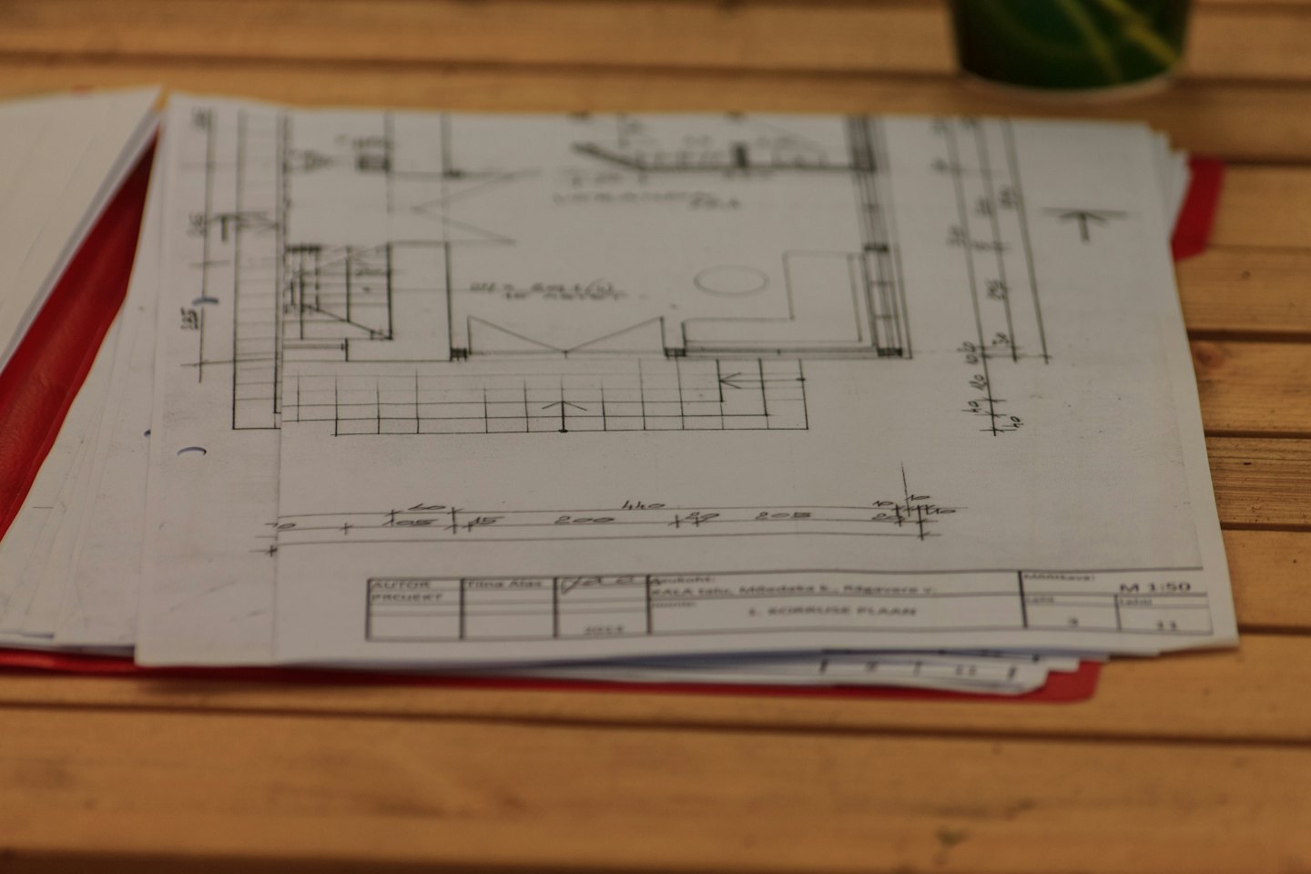Stack of architectural blueprints on a wooden desk.